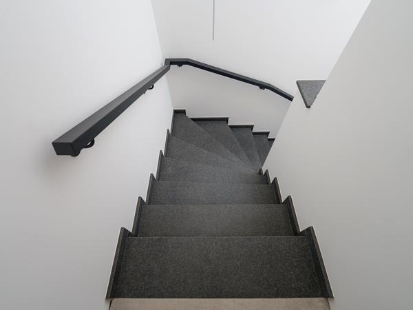 Geflieste Treppe mit dunklen Treppenfliesen und Handlauf