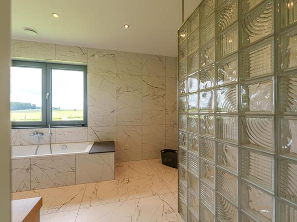 Badezimmer mit Marmoroptik-Fliesen und Glasbausteinen